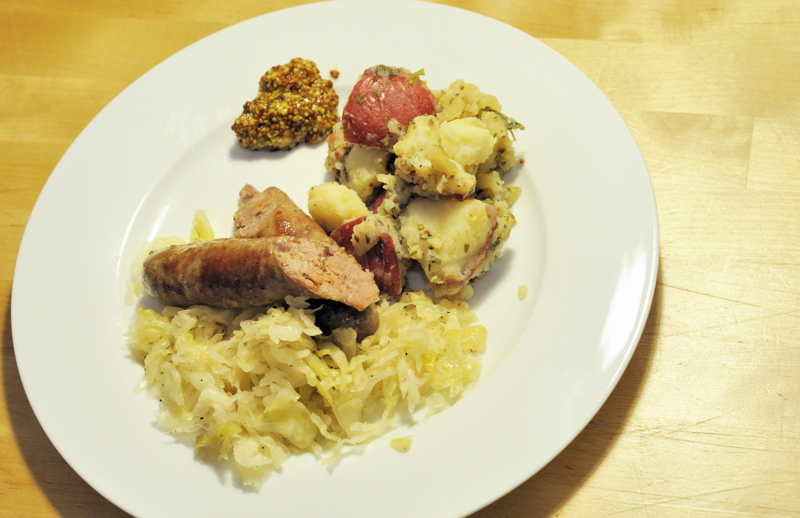 Sauerkraut, pork sausage, German potato salad, with some grainy mustard.